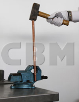 Copper-bonded rod driven with a hammer between the jaws of a vice